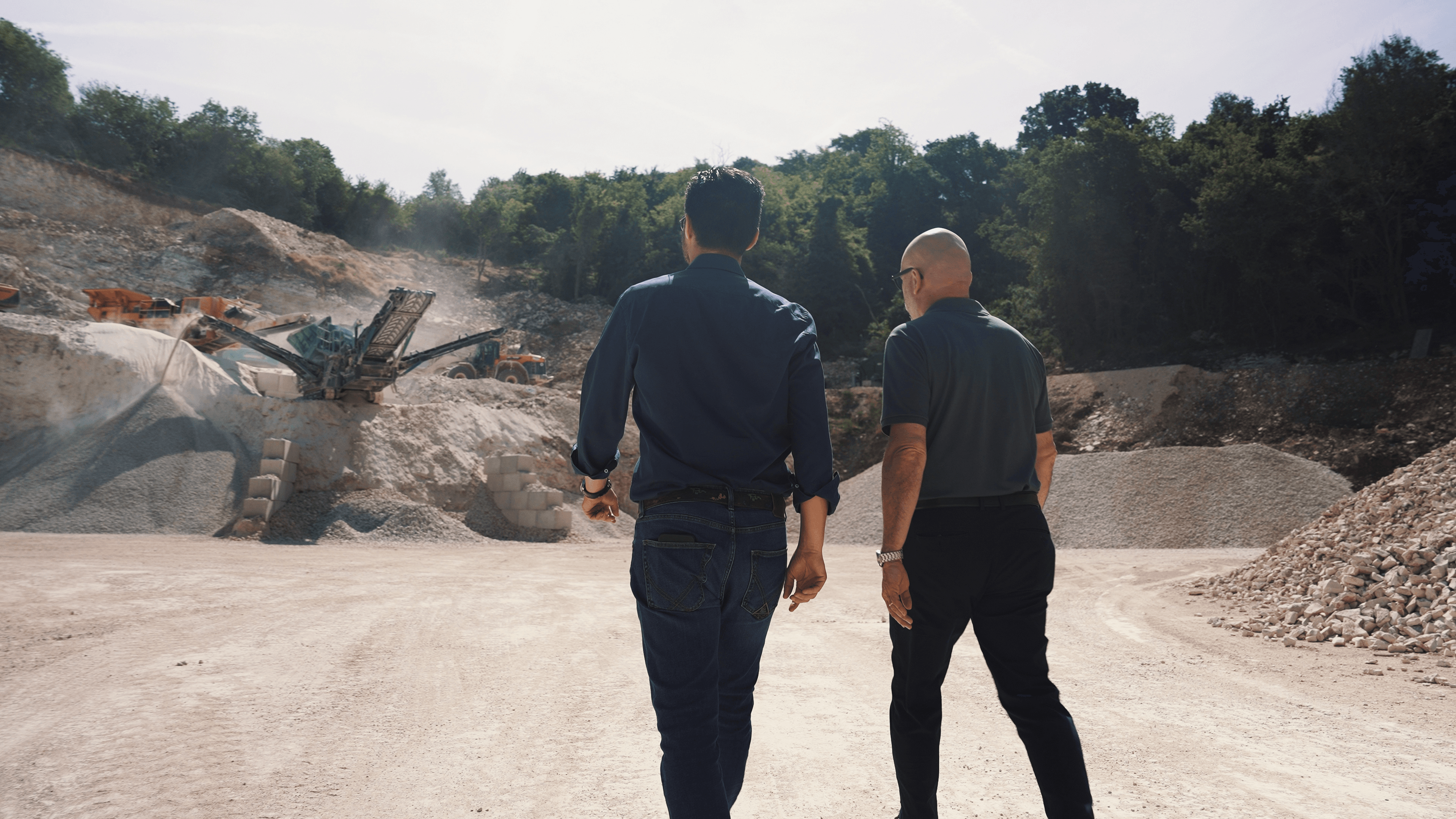 Representatives from BRB and DLL Equipment Showroom walk toward the Powerscreen Warrior 1400X screening plant at a quarry site in Italy following its successful sale and delivery.